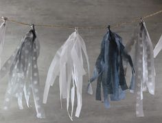 some white and blue feathers hanging from a line on a string with polka dotes