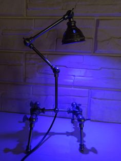 a lamp that is on top of a table in front of a brick wall and blue light