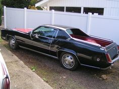 a black car parked in front of a white fence