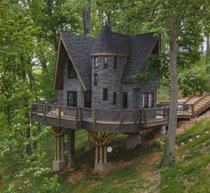 a house built into the side of a hill surrounded by trees and grass with stairs leading up to it