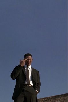 a man in a suit and tie talking on a cell phone while standing next to a building