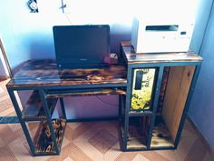 a desk with a computer on top of it next to a printer and other items