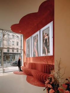 a woman standing in front of a window with pictures on the wall next to it