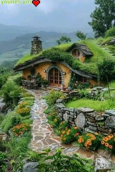 an image of a small house with grass on the roof and flowers in the yard