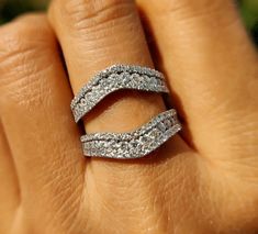 a woman's hand with two wedding bands on her finger and the ring has three rows of diamonds in it