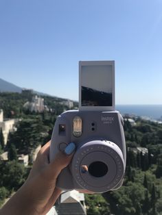 a person holding up a camera to take a photo with the city in the background