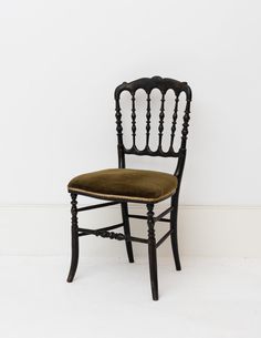 a black chair with a brown seat and back cushion against a white wall in an empty room