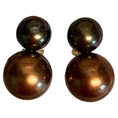 Black and bronze colored Tahitian pearls are featured in these Due Perla (two pearl) drop earrings. The black pearl measures 9mm. It is very dark with the slightest undertone of pistachio. The larger pearl measures 12.5mm. It is a rich bronze color. Both pearls are gem quality with excellent finish and luster. The pearl mountings are 18k yellow gold with posts and omega clip backs for added security. These tailored and business-like earrings are a one-of-a-kind creation by master goldsmith Micha Tahitian Pearls, Pearl Drop Earrings, Black Pearl, Bronze Color, Tahiti, Pearl Drop, Pistachio, E Business, Jewelry Earrings