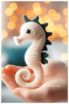 crocheted seahorse in the palm of someone's hand with christmas lights in the background