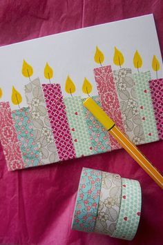 a birthday card with candles on it next to rolls of washi tape and a pencil