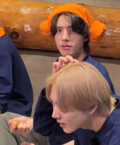 two young men sitting next to each other in front of a wooden log and wearing orange headbands