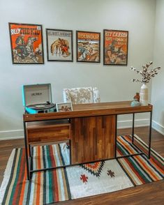 an office with posters on the wall and a rug in front of it, along with a computer desk