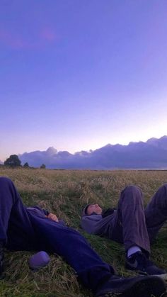 two men laying on the ground in a field