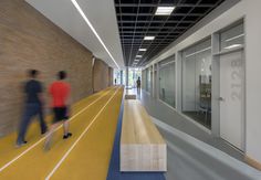 two people walking down a long hallway in an office building