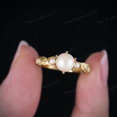 a woman's hand holding a pearl ring