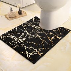 a black and gold bathroom rug next to a toilet