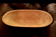 a wooden bowl sitting on top of a leather couch