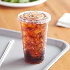 a plastic cup filled with soda sitting on top of a tray