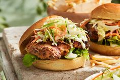 a sandwich with meat, lettuce and coleslaw on a wooden table