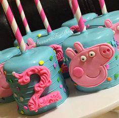 the cake pops are decorated with pink and blue frosting, peppa's birthday candles