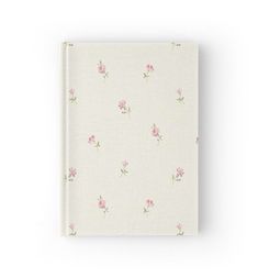 a white notebook with pink flowers on the front and bottom cover, sitting against a white background