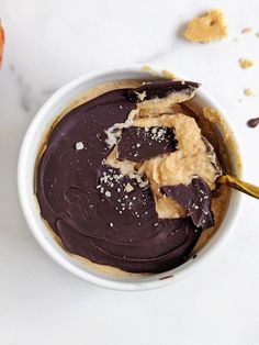 a white bowl filled with chocolate frosting next to an orange and crackers on the table