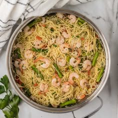 a pan filled with noodles and shrimp on top of a table