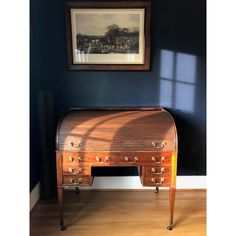 an old wooden desk sitting in front of a painting