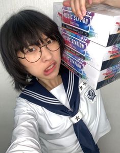 a woman wearing glasses and holding stacks of books