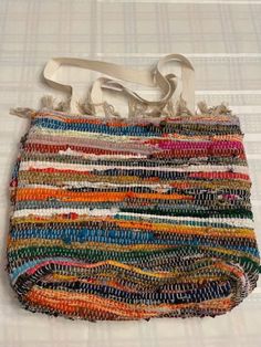 a multicolored handbag sitting on top of a white tablecloth covered floor