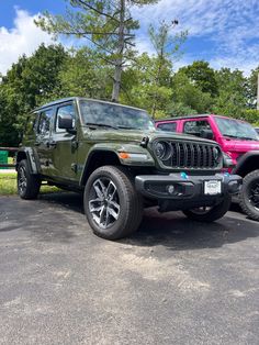 two jeeps parked in a parking lot next to trees and bushes on a sunny day