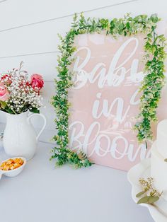 a baby is in bloom sign next to flowers and other items on a table with cake