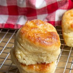 two biscuits stacked on top of each other on a wire rack next to a red and white checkered napkin