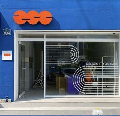 a blue building with an orange and white sign on it's glass door that says design yourself