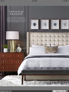 a bedroom with gray walls, white bedding and two lamps on either side of the bed