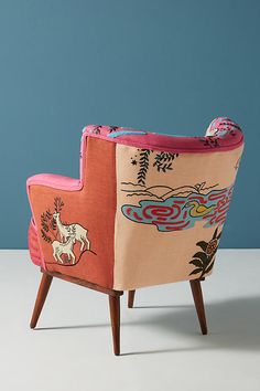 an upholstered chair with designs on the back and arm rests against a blue wall