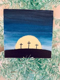 an ornament hanging from a christmas tree with three crosses painted on it