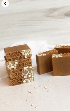 three pieces of soap sitting next to each other on a white tablecloth with gold foil