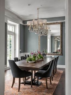 a dining room table with black chairs and a chandelier hanging from the ceiling