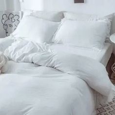 a bed with white sheets and pillows in a room