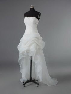 a white wedding dress on a mannequin in front of a gray background,