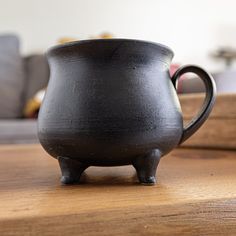 a black pot sitting on top of a wooden table