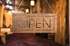 a wooden sign that says open hanging from the ceiling