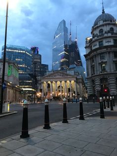 an empty city street at dusk with tall buildings in the background and traffic lights on either side