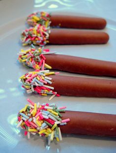 three hot dogs with sprinkles are on a plate