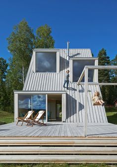 a person standing on top of a wooden deck in front of a house with windows