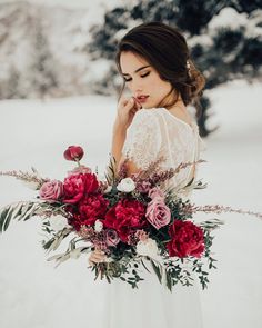 a woman holding a bouquet of flowers in the snow with her hand on her face