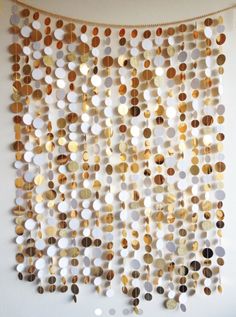 a wall hanging made out of different types of buttons and circles on a white wall