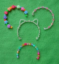 a mickey mouse head made out of beads and other items on a green cloth background