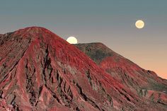 the mountains are covered in red rocks and moon's light shines on them